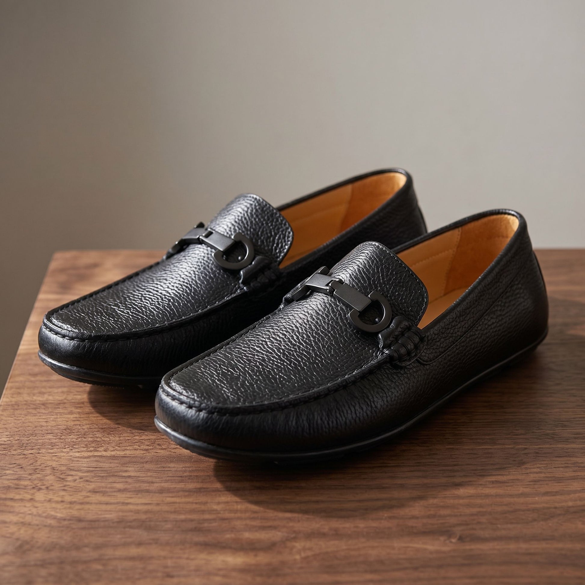 Reversible black milled leather shoes with metal fittings showcased on a dark wooden surface, highlighting craftsmanship and material quality.
